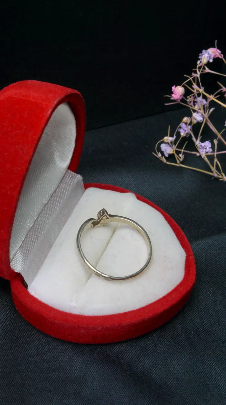 Vintage delicate silver ring in an open red velvet jewelry box with white satin lining.