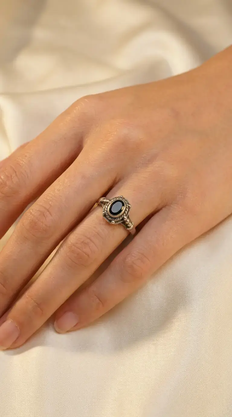 Vintage sterling silver black onyx oval ring with braided bezel on a woman's hand.