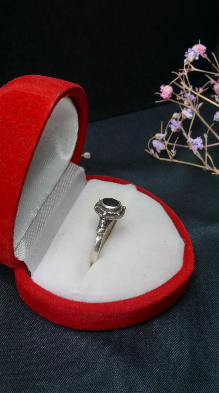 Vintage sterling silver ring with black onyx stone in open red velvet heart-shaped jewelry box