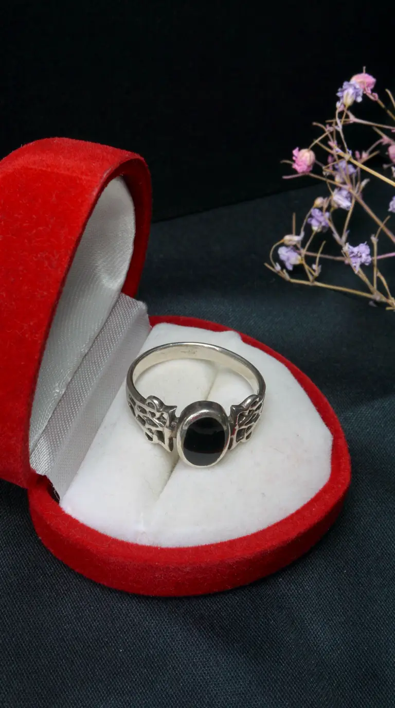 Vintage sterling silver ring with oval black onyx stone and intricate band design, in open red velvet jewelry box