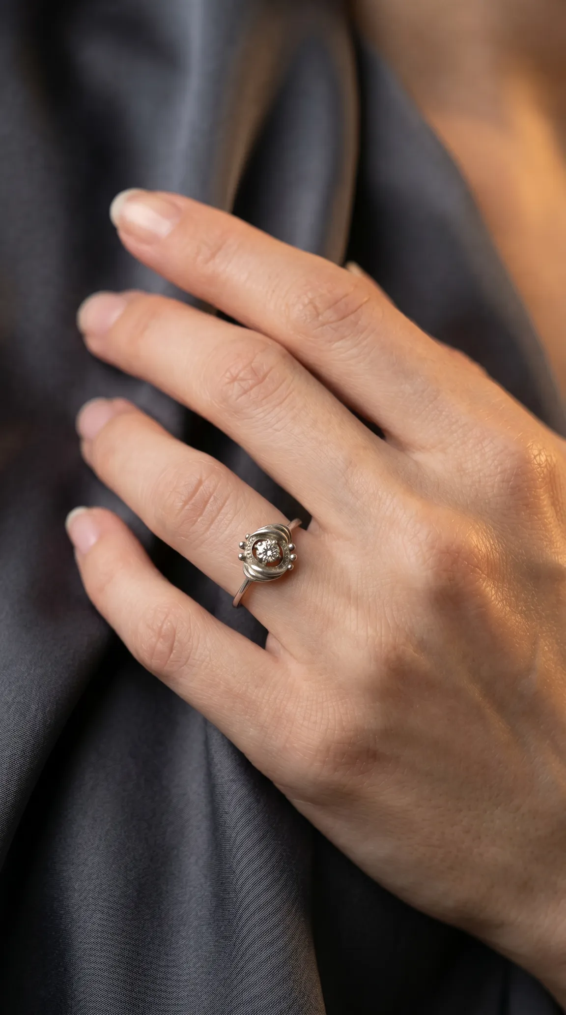 Vintage diamond ring with swirled silver setting and bead accents on a woman's hand.