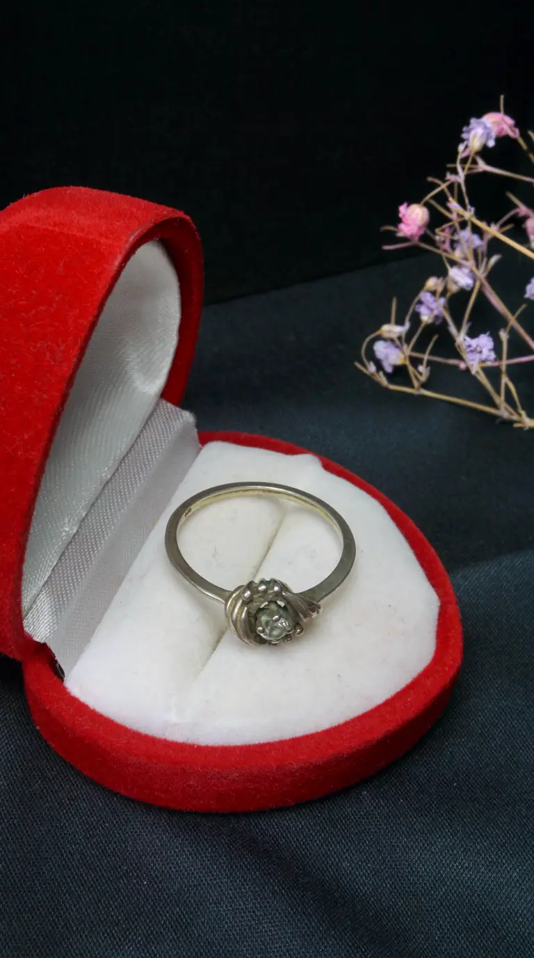Antique silver ring with sparkling light gemstone in unique setting, presented in red velvet jewelry box.