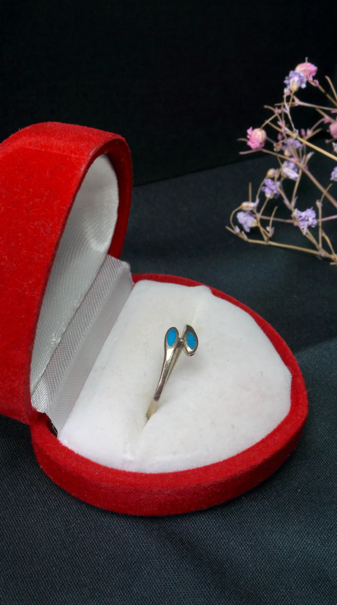 Vintage silver ring with two turquoise gemstones in an open red velvet jewelry box.