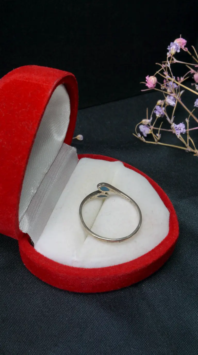 Vintage sterling silver bypass ring with light blue enamel accents in a red heart-shaped velvet box.
