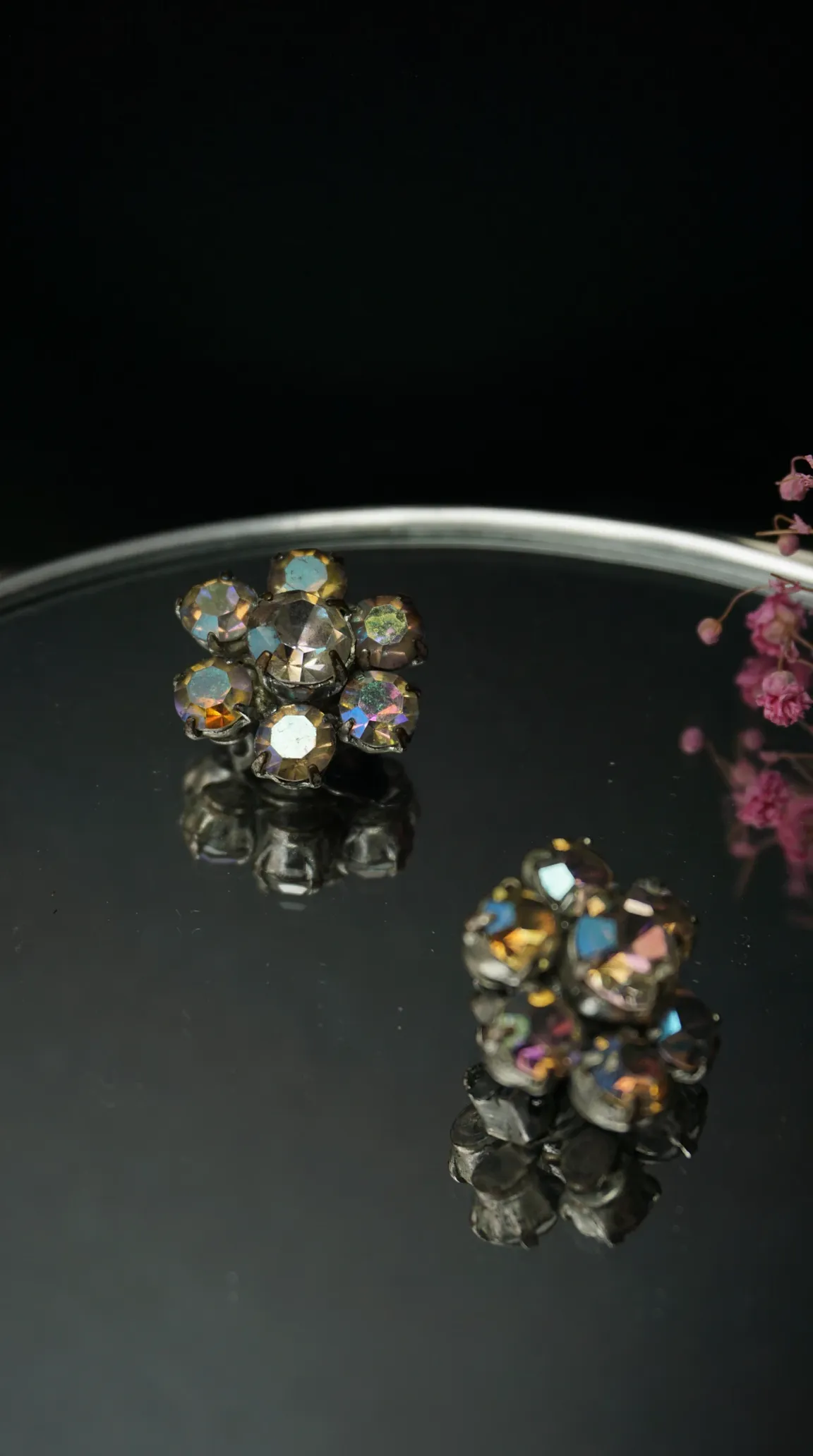 Vintage aurora borealis rhinestone flower cluster earrings on reflective surface
