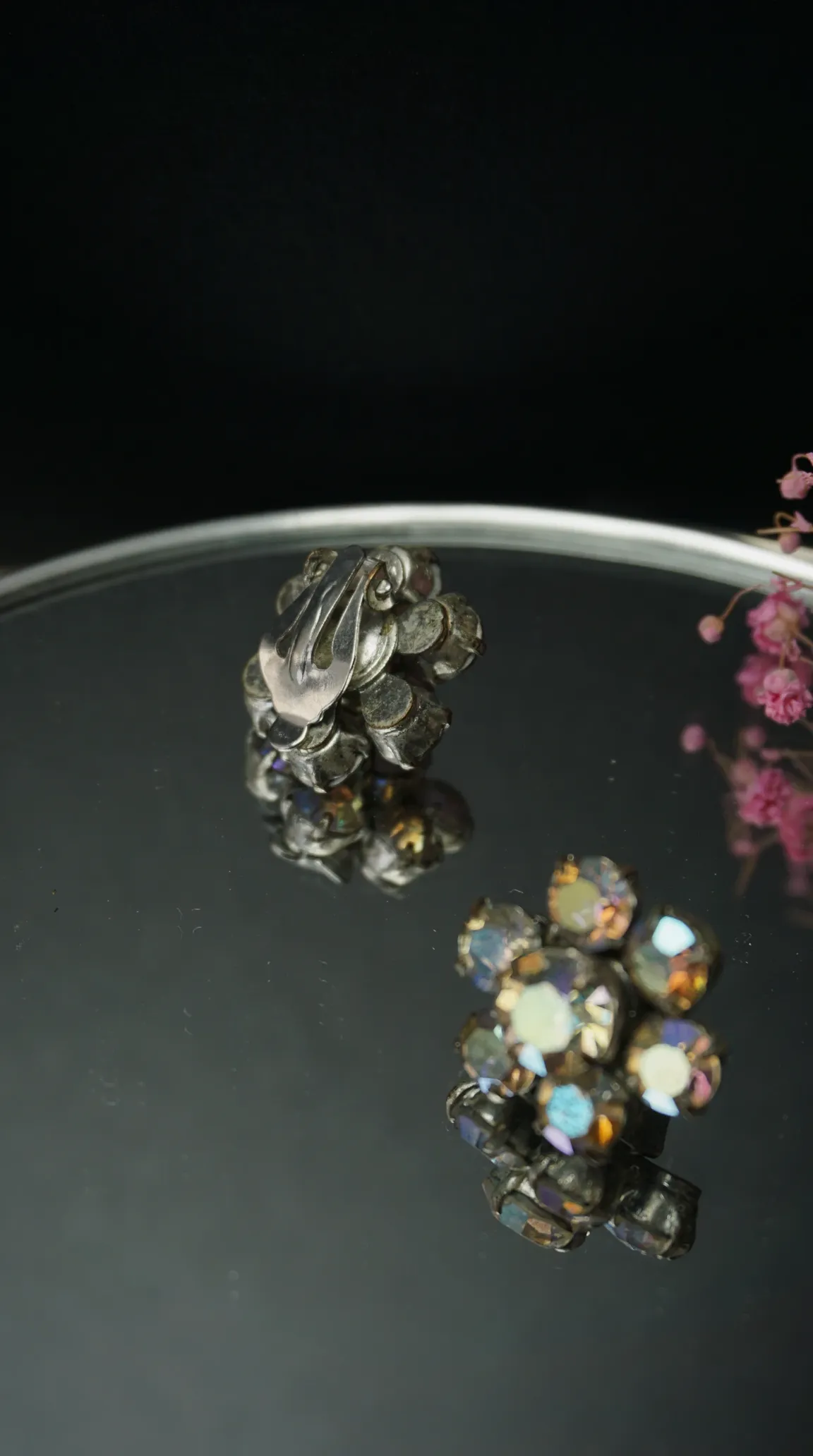 Vintage aurora borealis rhinestone floral cluster clip-on earrings on a reflective surface, showing front and back.