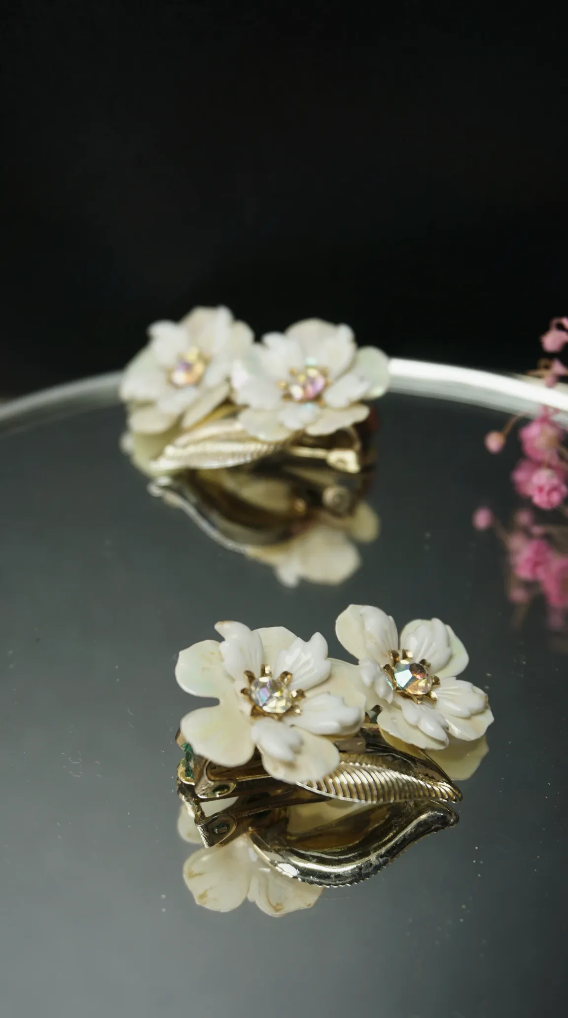 Vintage white mother-of-pearl floral brooches with iridescent rhinestone centers and gold-tone leaves.