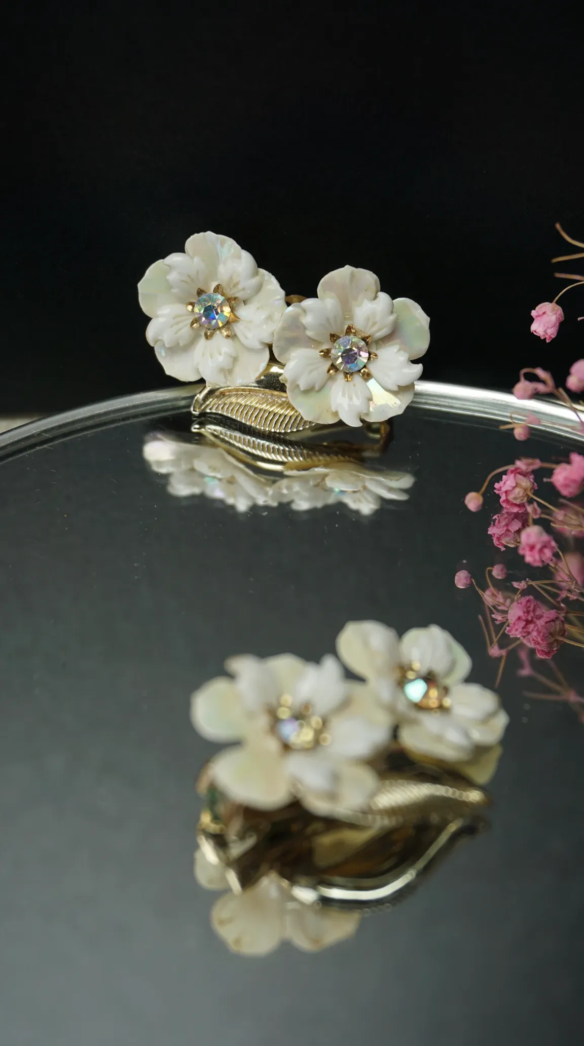 Vintage mother of pearl floral earrings with iridescent rhinestone centers and gold tone leaf setting.