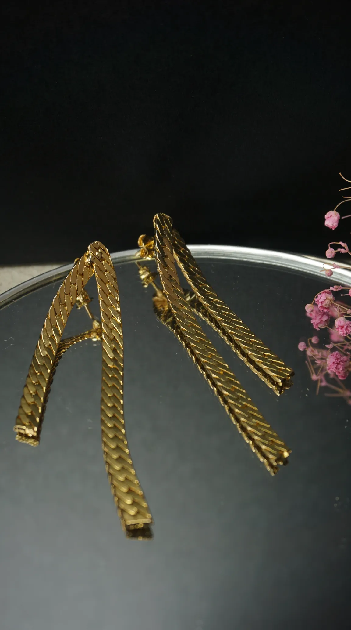 Vintage gold flat chain dangle earrings on a mirrored surface.
