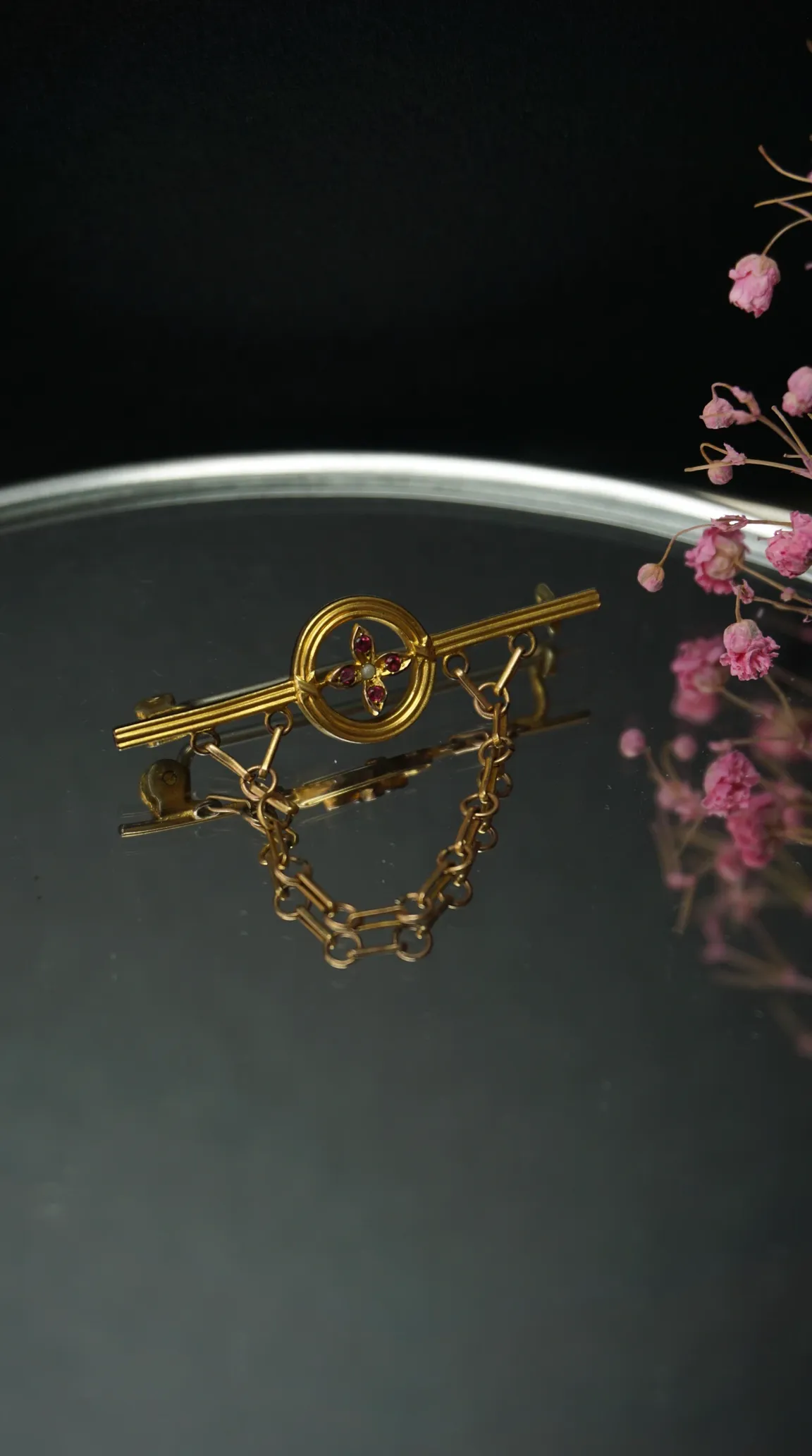 Vintage gold key design brooch with ruby gemstones, pearl, and attached chain.