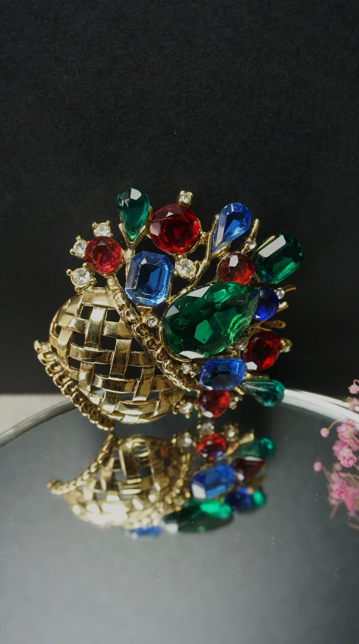 Vintage gold-tone woven basket brooch with colorful red, green, and blue faceted gemstones and sparkling clear rhinestones.