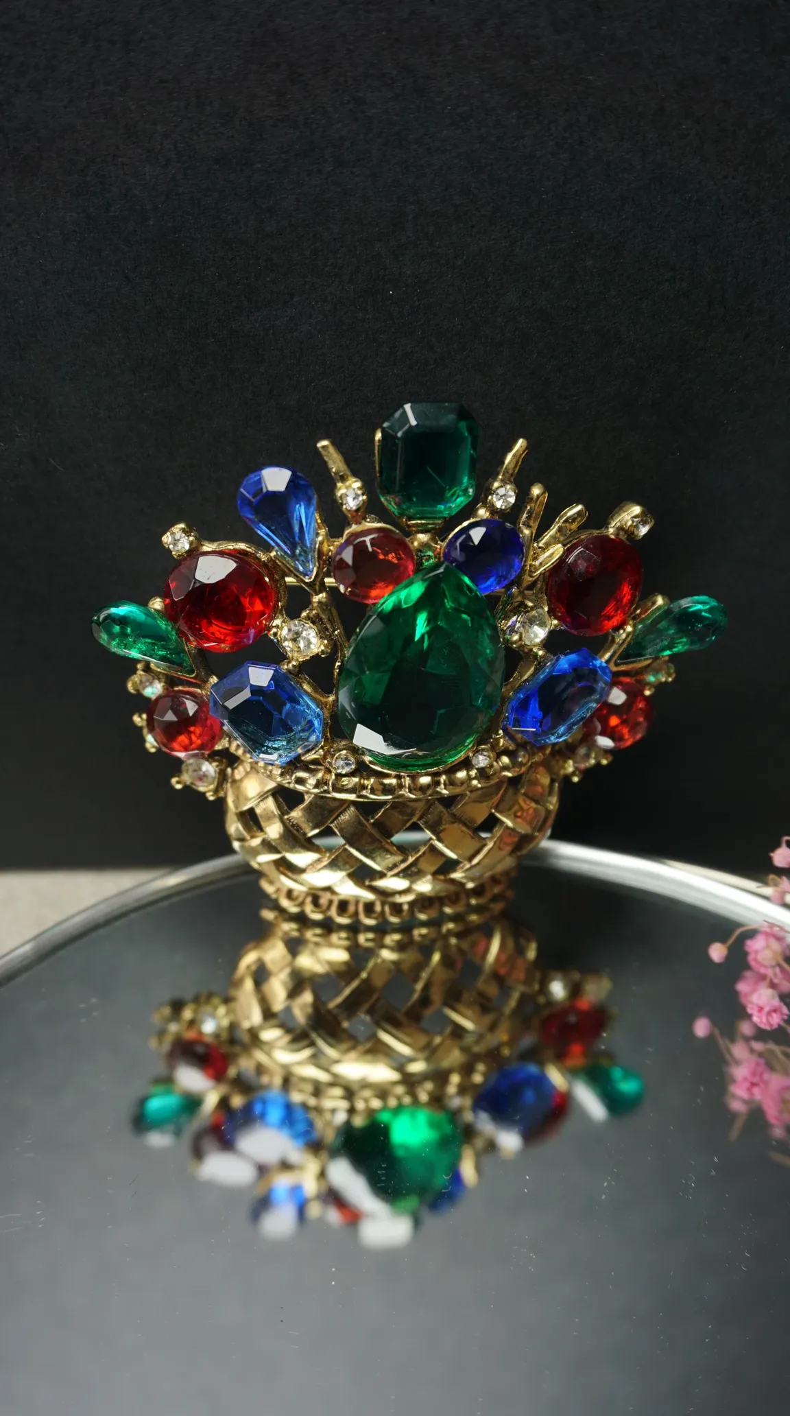Vintage gold tone basket brooch with vibrant red, green, and blue faceted rhinestones.