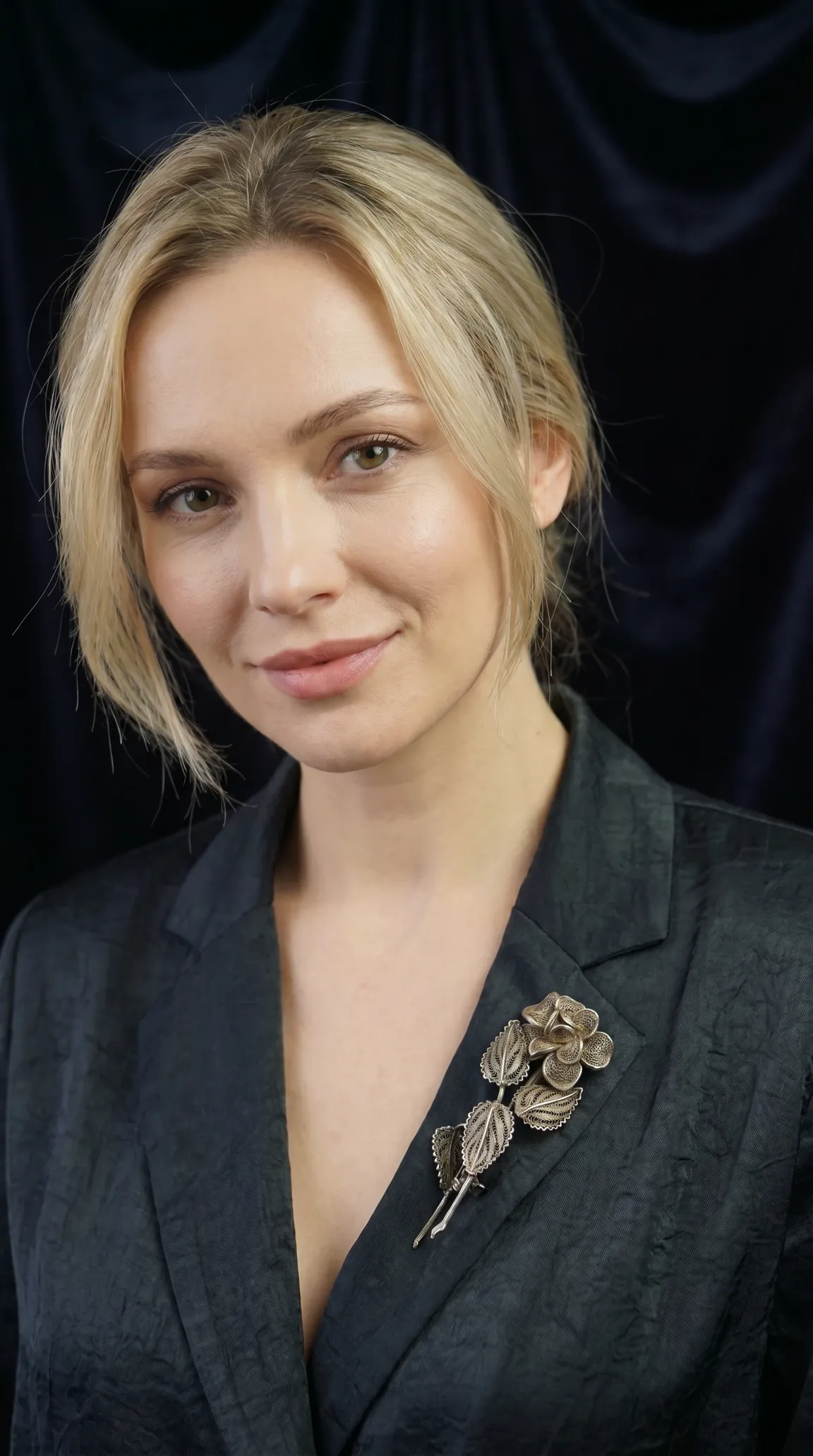 Vintage filigree flower and leaf brooch on dark blazer, worn by blonde model, showcasing elegant silver-toned antique jewelry.