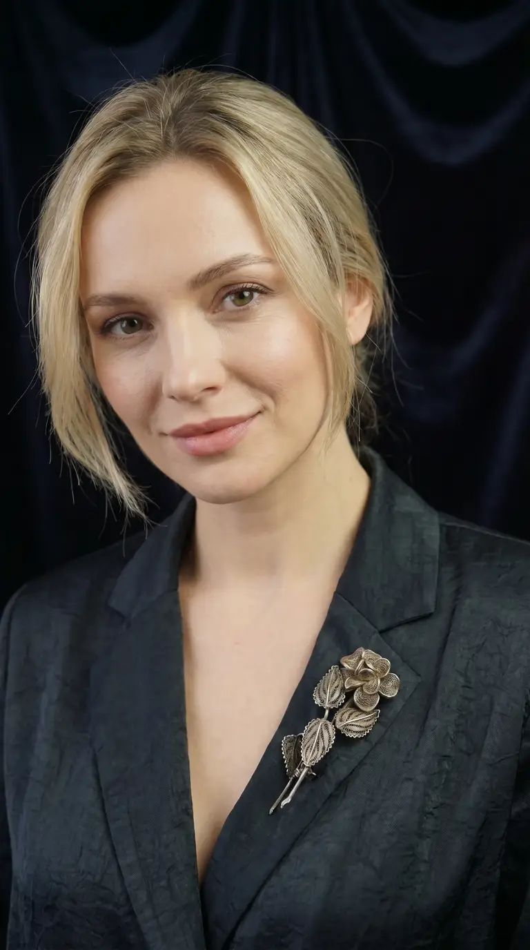 Vintage filigree flower and leaf brooch on dark blazer, worn by blonde model, showcasing elegant silver-toned antique jewelry.