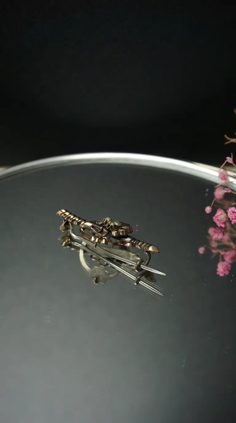 Vintage gold-tone crossed sword brooch with pearl details on a reflective surface.