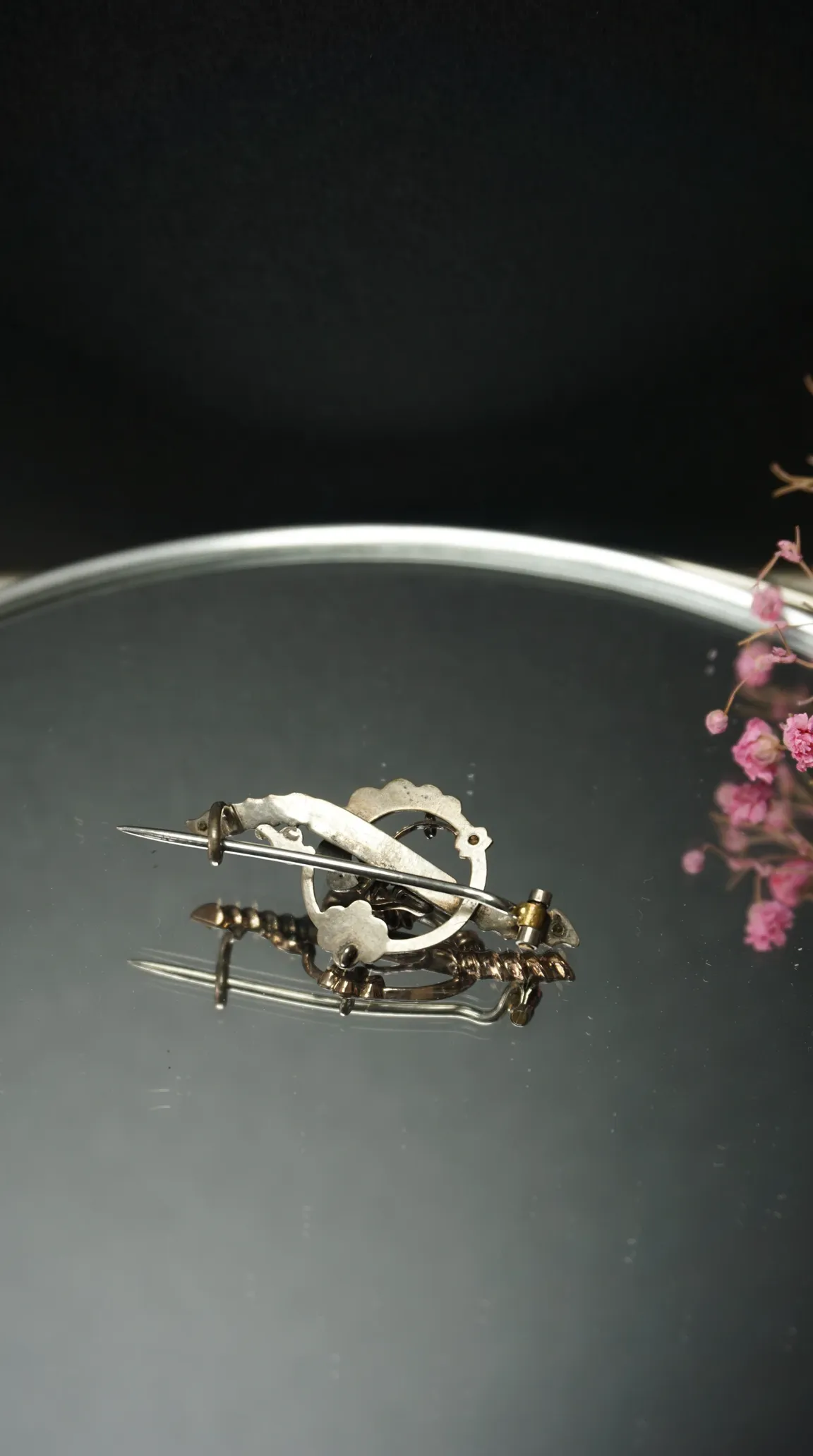 Vintage silver tone brooch pin clasp mechanism on reflective surface