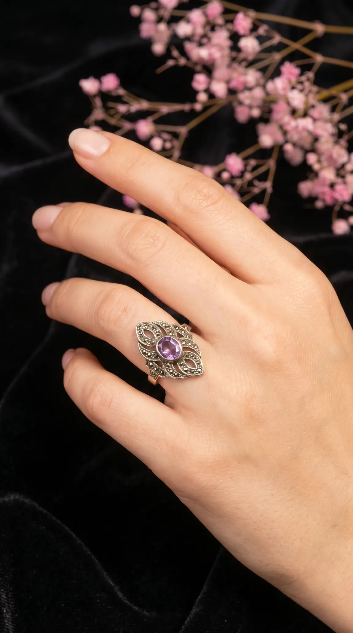 Vintage Art Deco sterling silver ring with oval amethyst and marcasite. Antique purple gemstone cocktail ring on a hand.