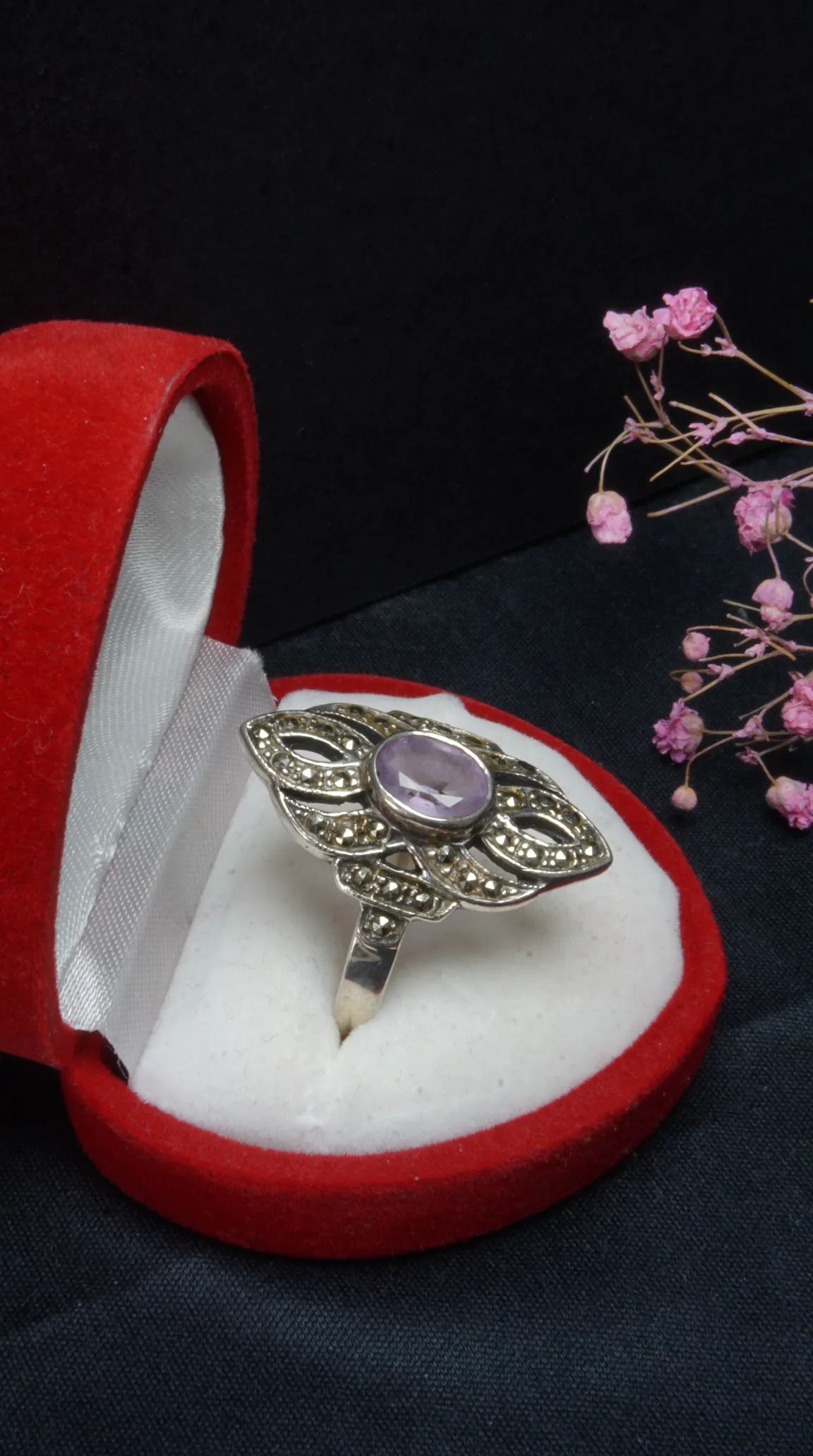Vintage sterling silver ring with oval purple amethyst gemstone and intricate marcasite filigree design in a red jewelry box.