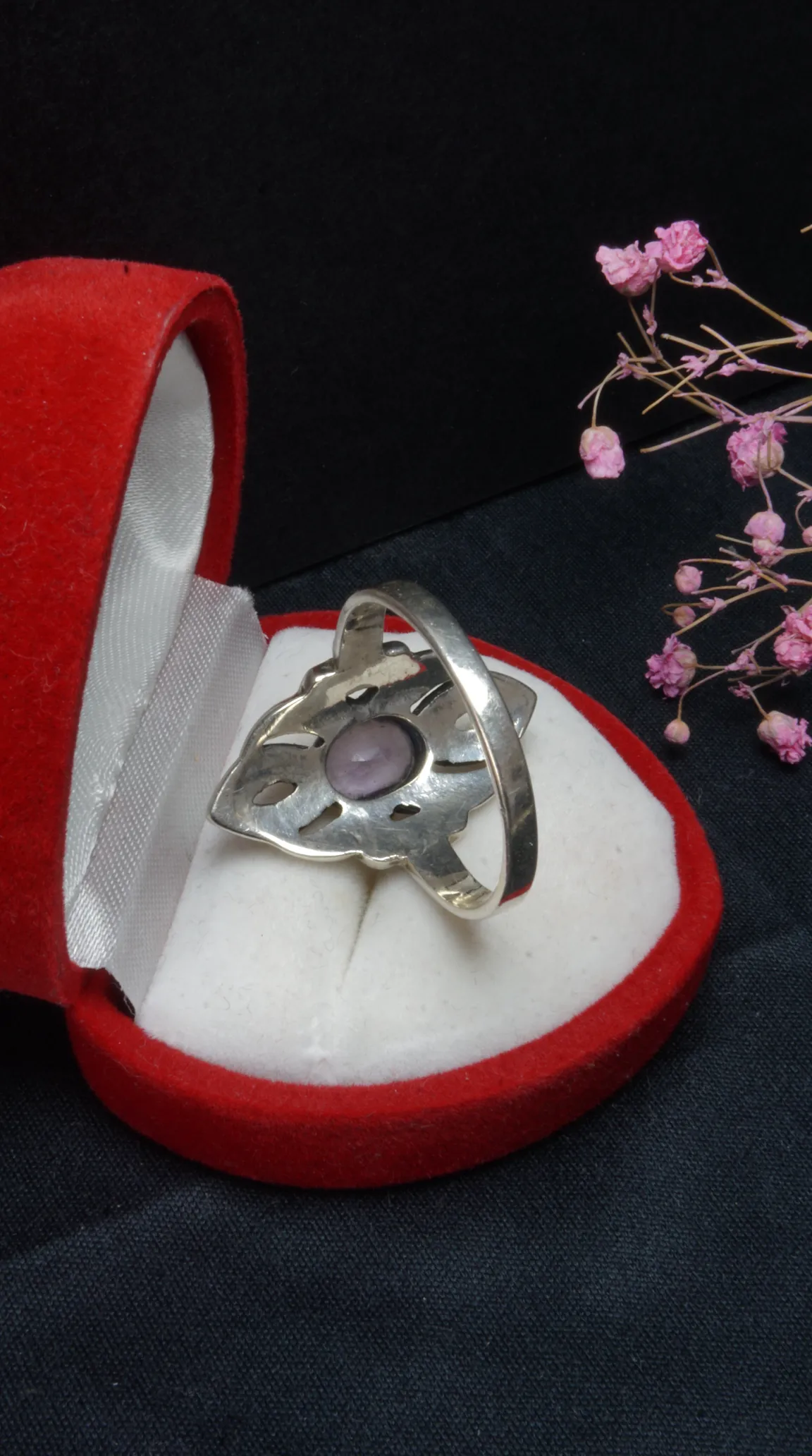 Vintage sterling silver ring with lavender gemstone, intricate design, in an open red velvet jewelry box.