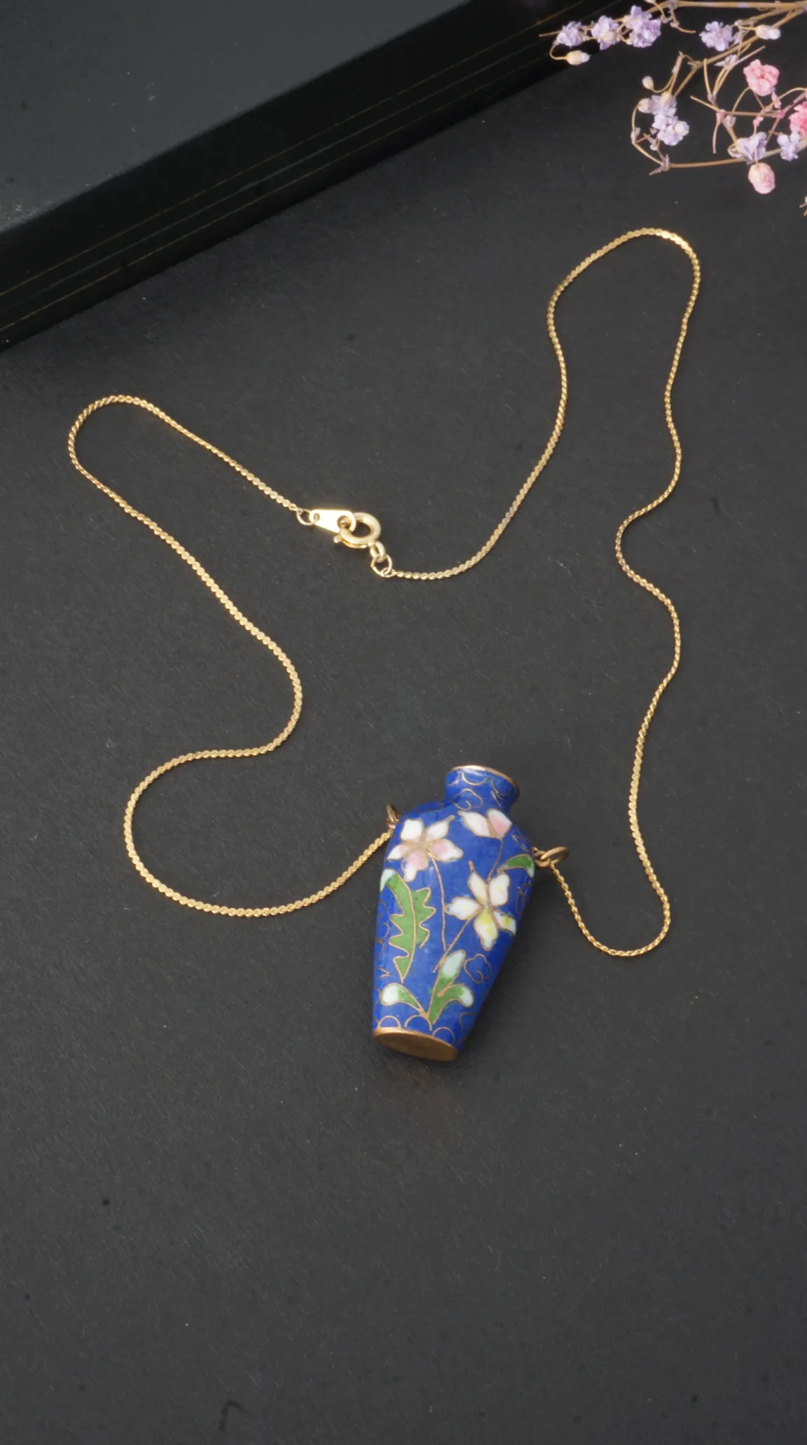 Vintage blue cloisonné enamel perfume bottle pendant necklace with white and pink floral design on a gold chain.