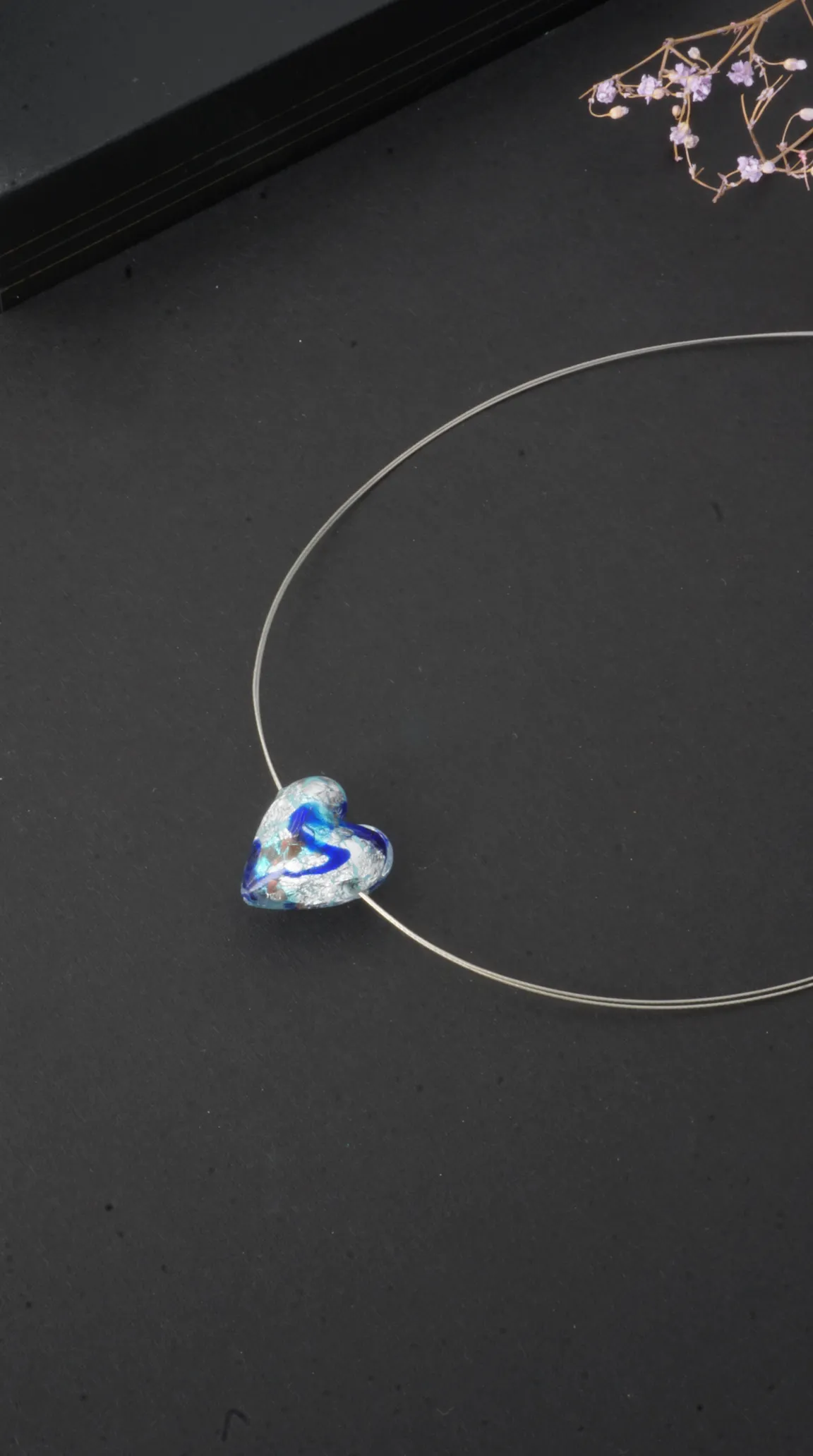 Vintage blue glass heart pendant necklace with silver swirls on a silver wire.