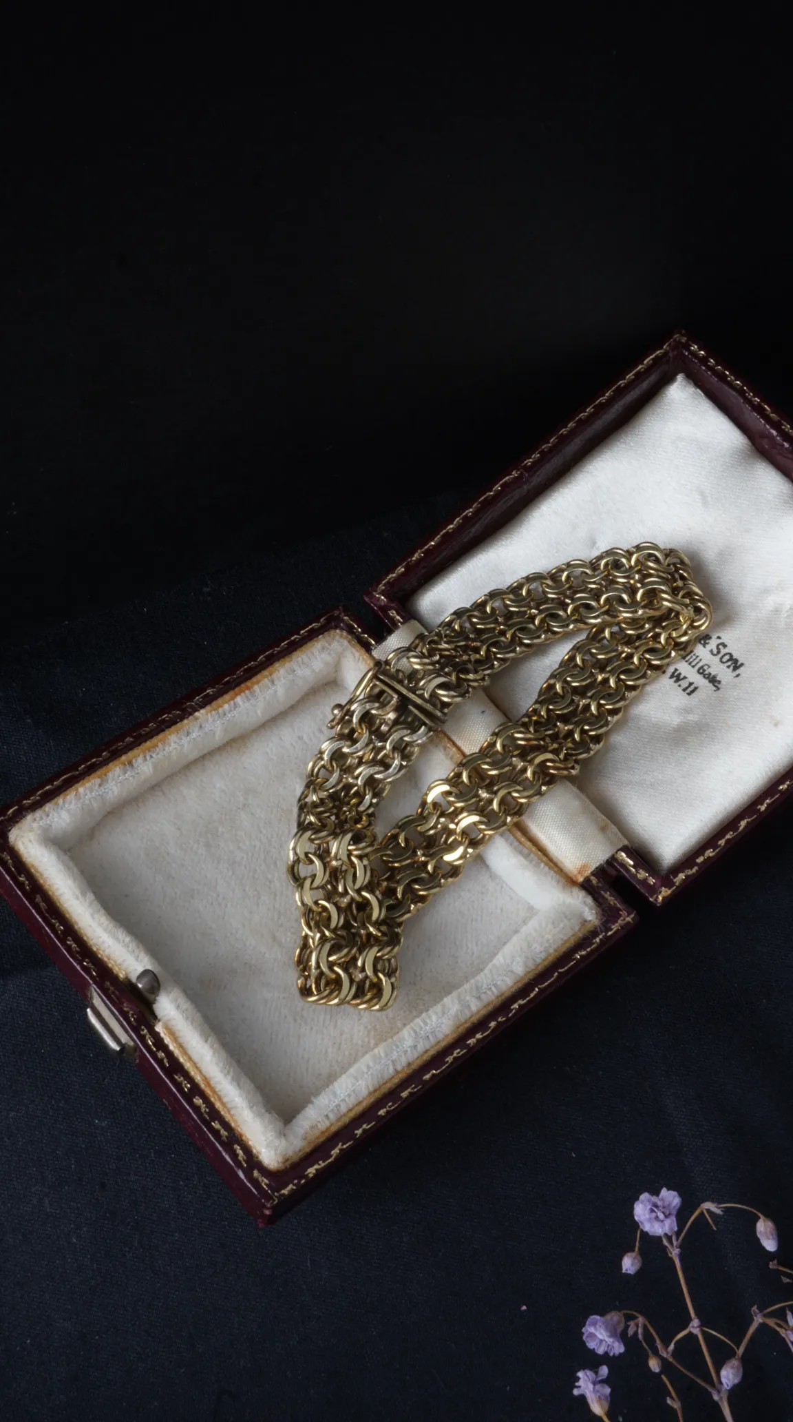 Vintage gold chain link bracelet displayed in antique maroon jewelry box with cream satin lining