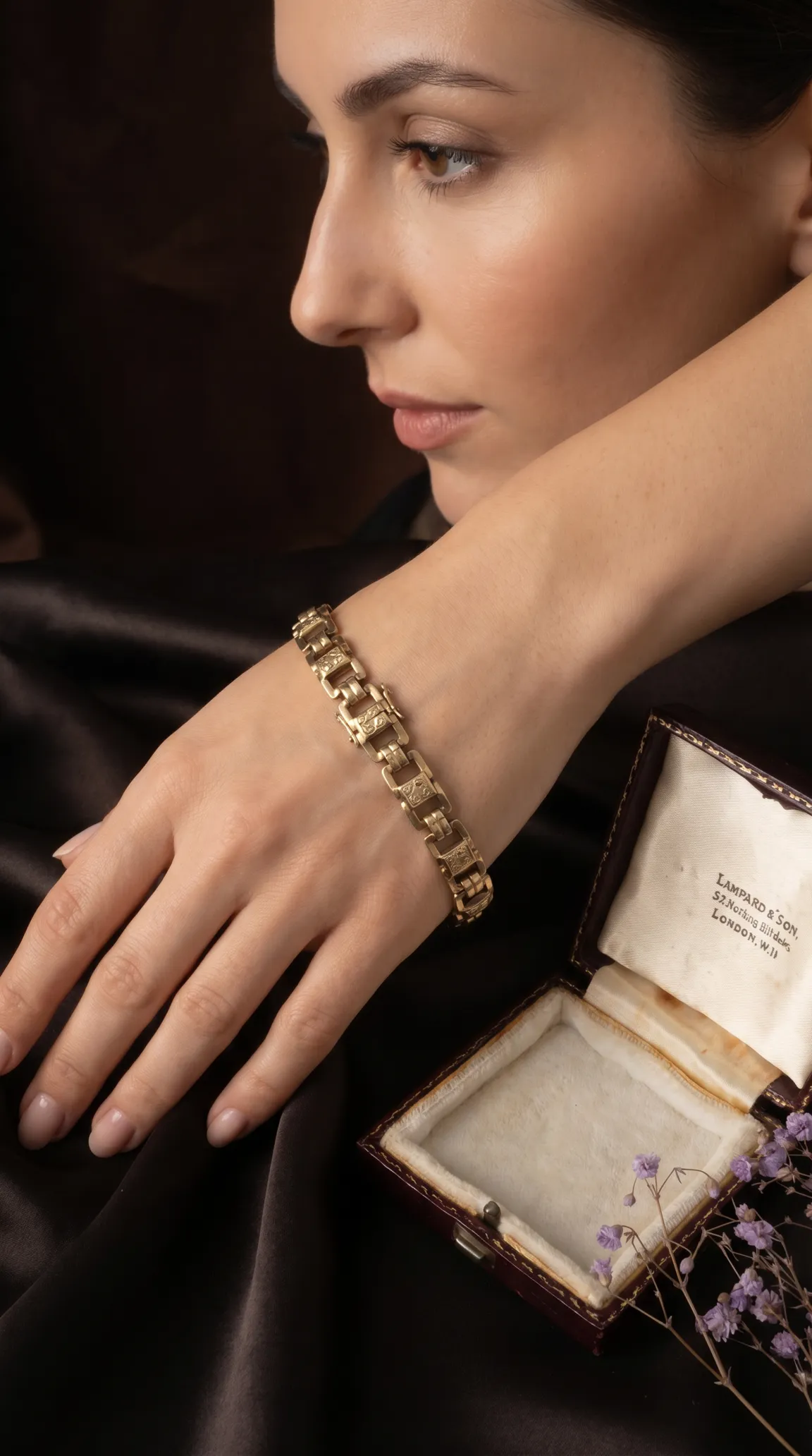 Vintage gold link bracelet with engraved patterns on a woman's wrist, displayed with an antique jewelry box for elegant women's vintage jewelry.