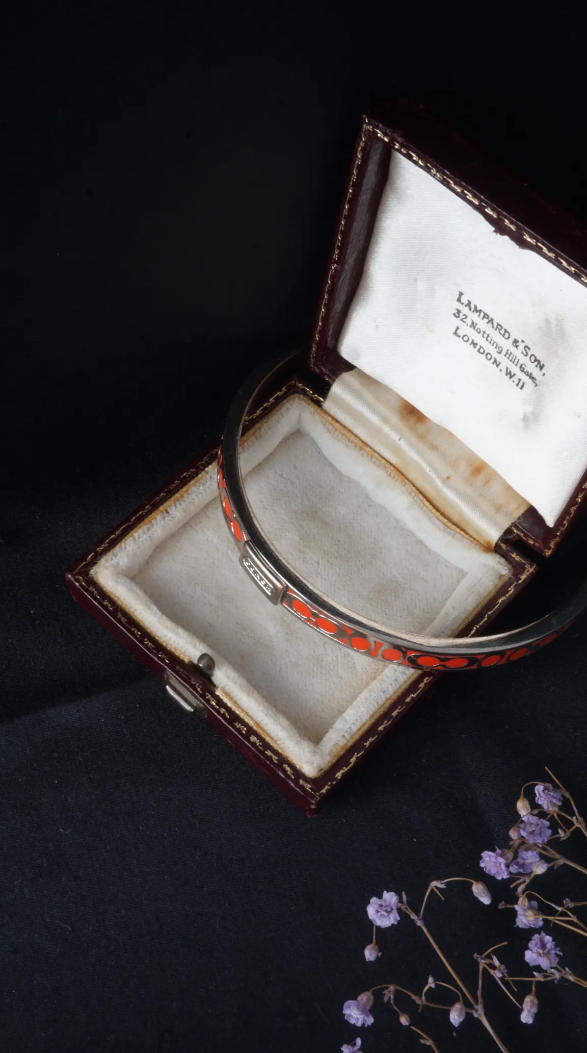 Vintage silver bangle with orange enamel pattern in antique Lampard & Son jewelry box.