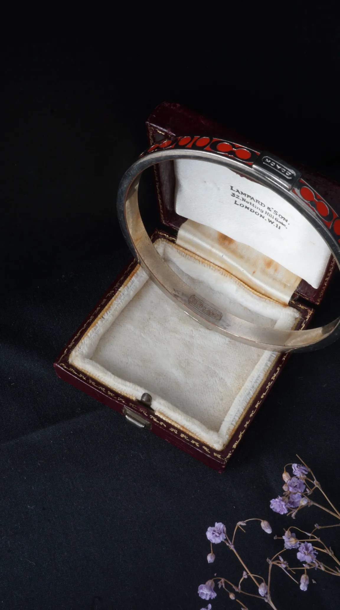 Vintage Coach silver bracelet with red enamel design in an open Lampard & Son London jewelry box on a dark background.