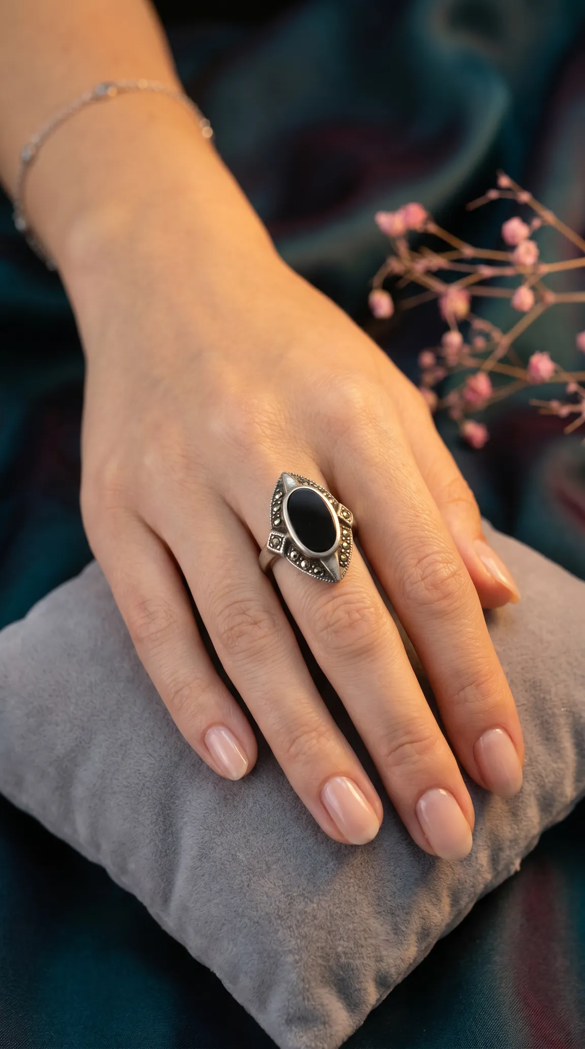 Vintage sterling silver ring with oval black onyx and marcasite details on a woman's hand, art deco style.