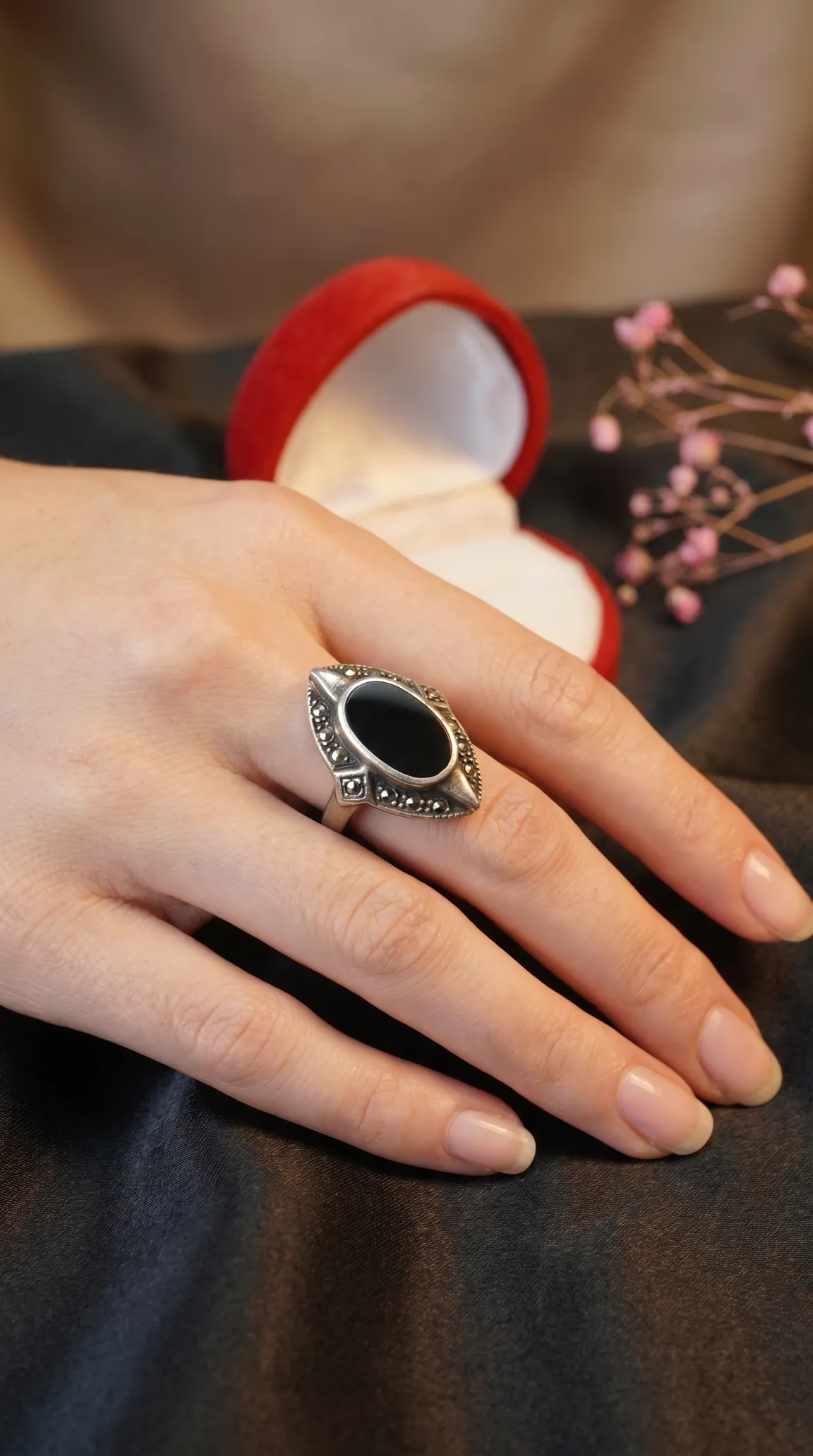 Vintage sterling silver ring with black onyx and marcasite, featuring a marquise center stone, on a woman's hand.