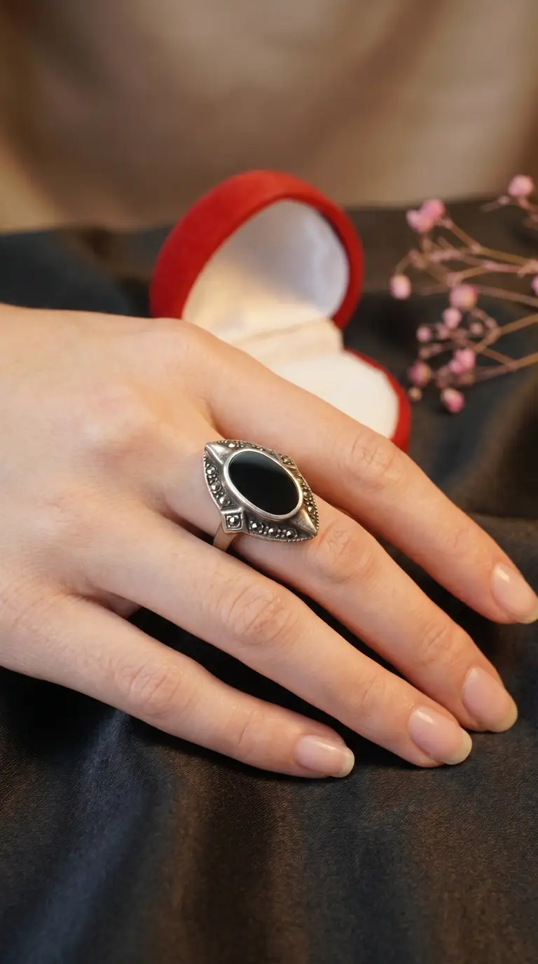 Vintage sterling silver ring with black onyx and marcasite, featuring a marquise center stone, on a woman's hand.
