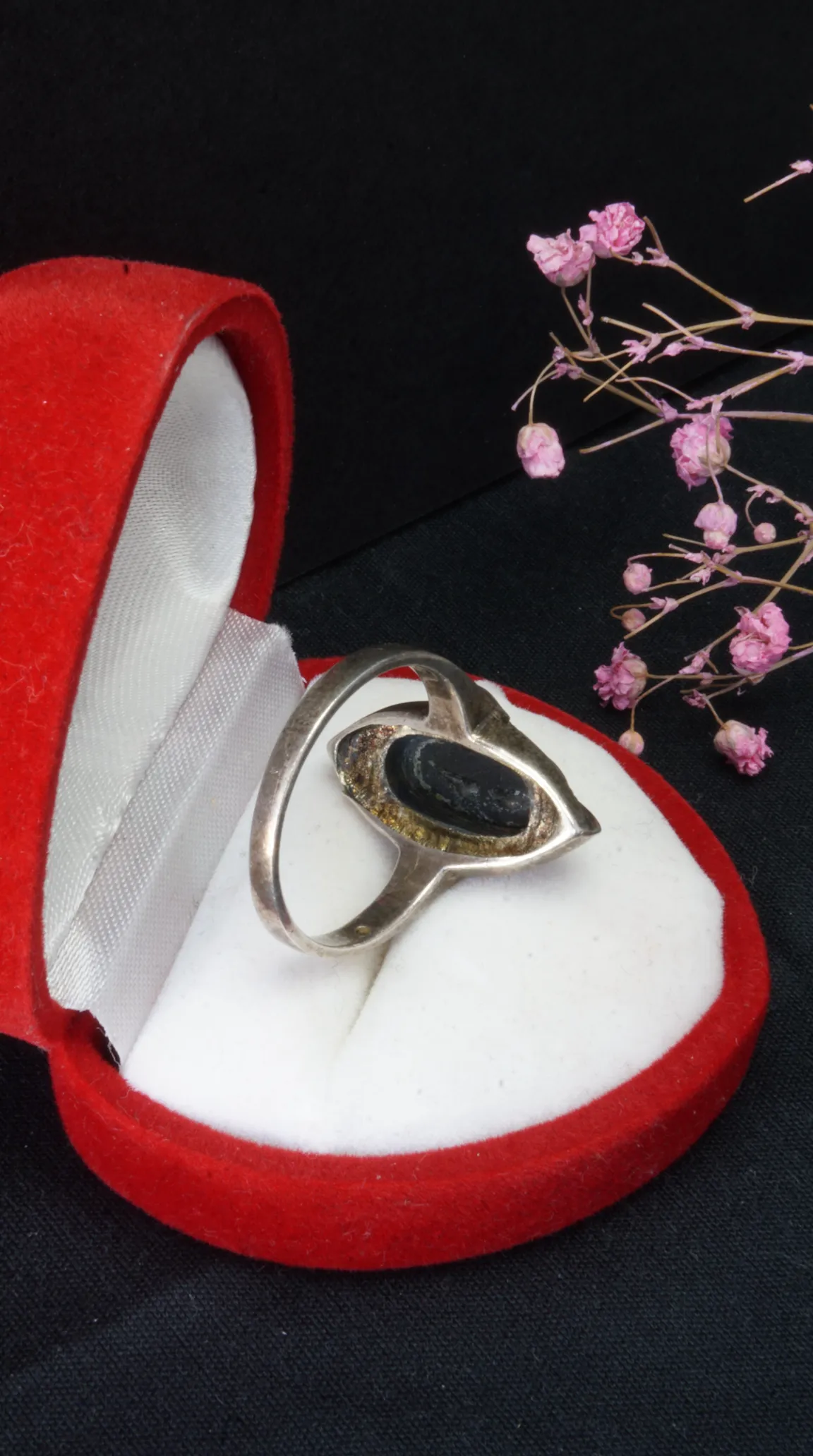 Vintage sterling silver ring with black elongated gemstone in abstract setting, displayed in open red heart-shaped jewelry box