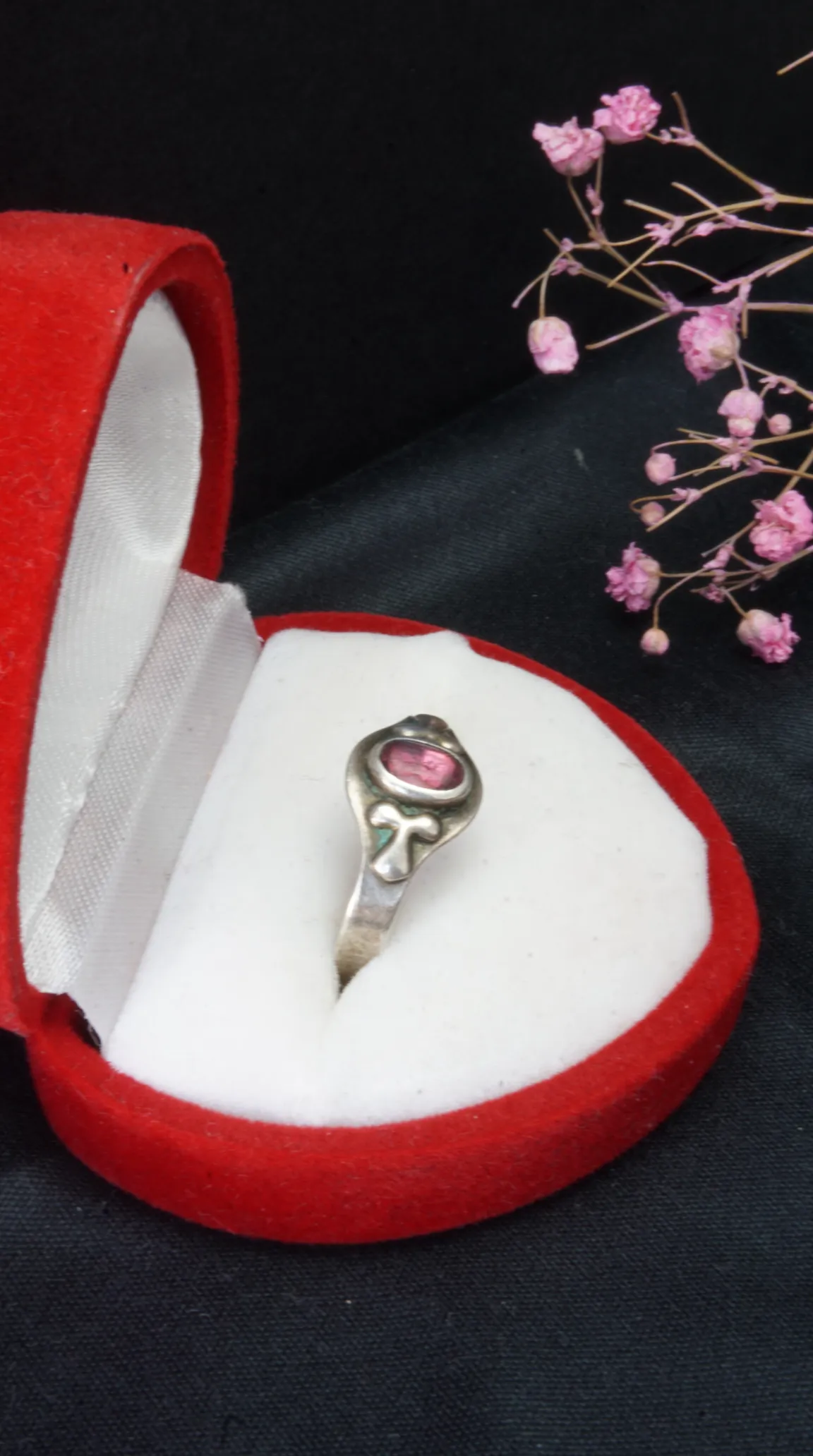 Vintage sterling silver ring with oval pink gemstone and ornate design in red velvet box.