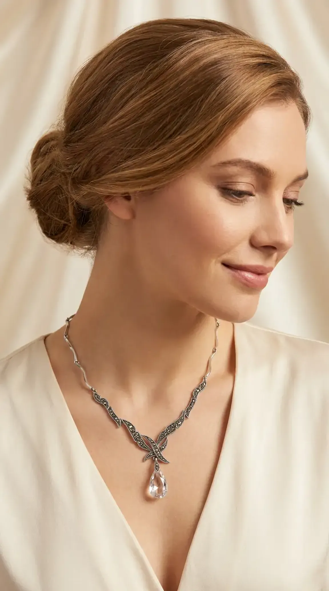 Vintage marcasite sterling silver necklace with pearl accents and large clear teardrop crystal pendant on model in black dress.