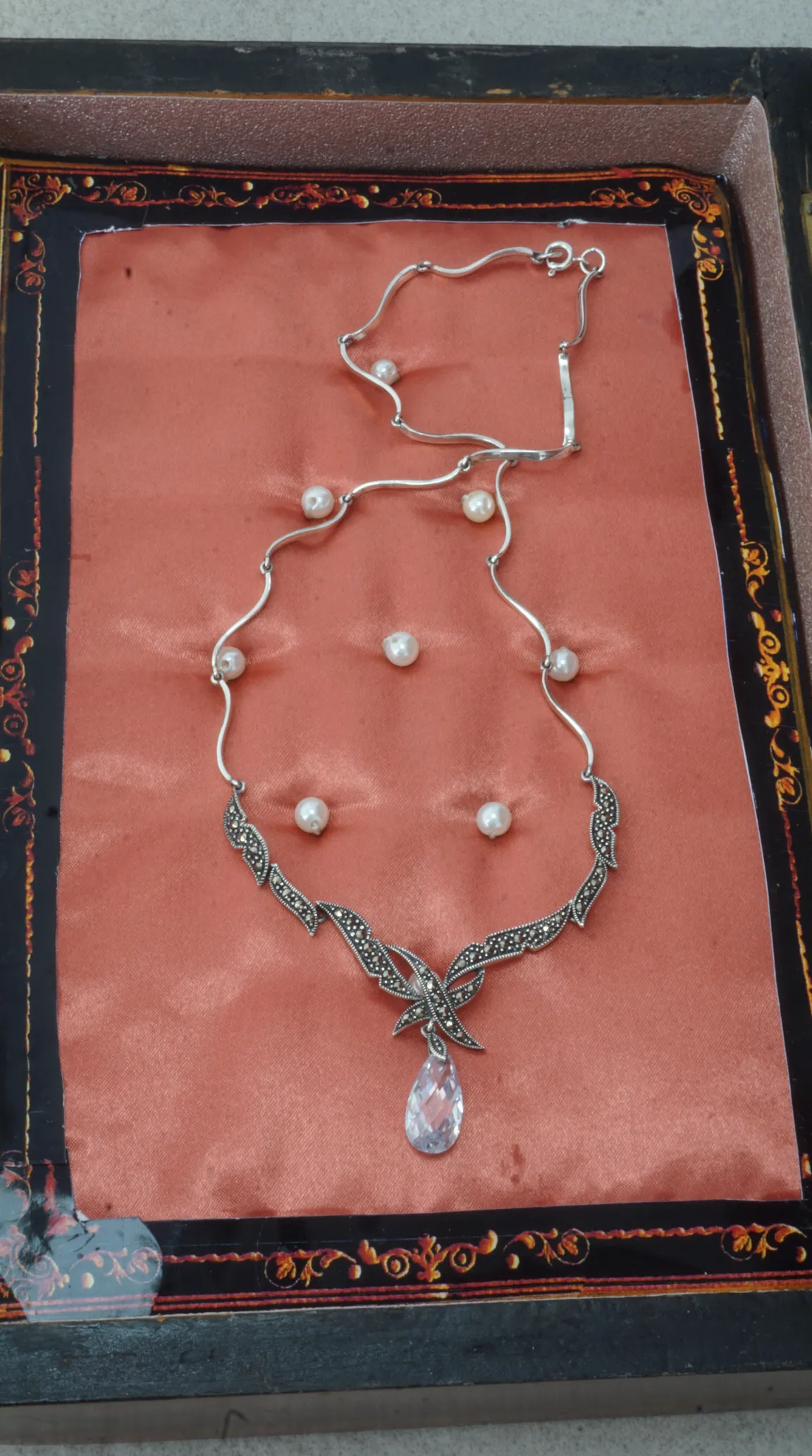 Vintage sterling silver marcasite and pearl necklace with clear teardrop crystal pendant displayed on peach satin.