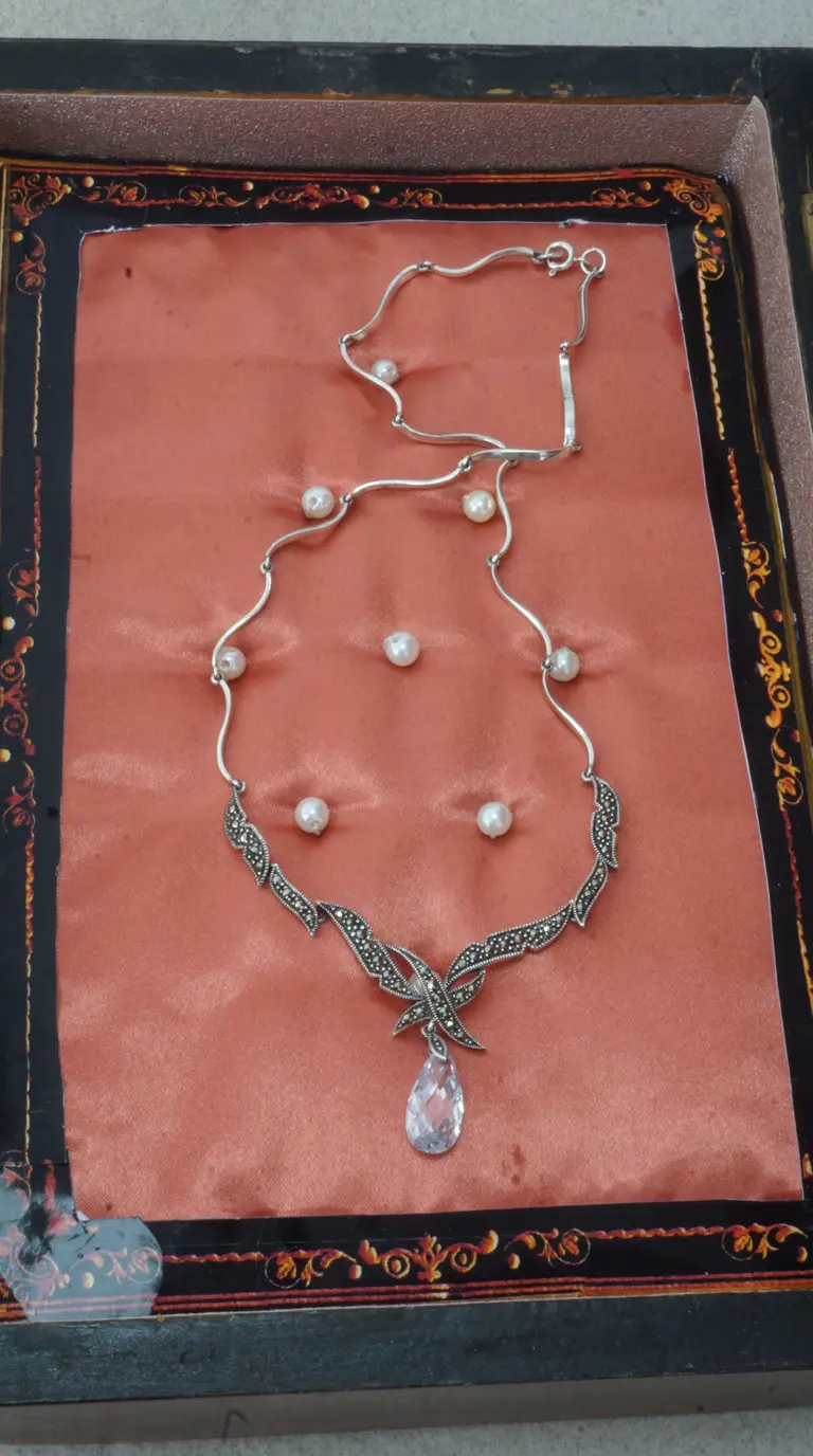 Vintage sterling silver marcasite and pearl necklace with clear teardrop crystal pendant displayed on peach satin.