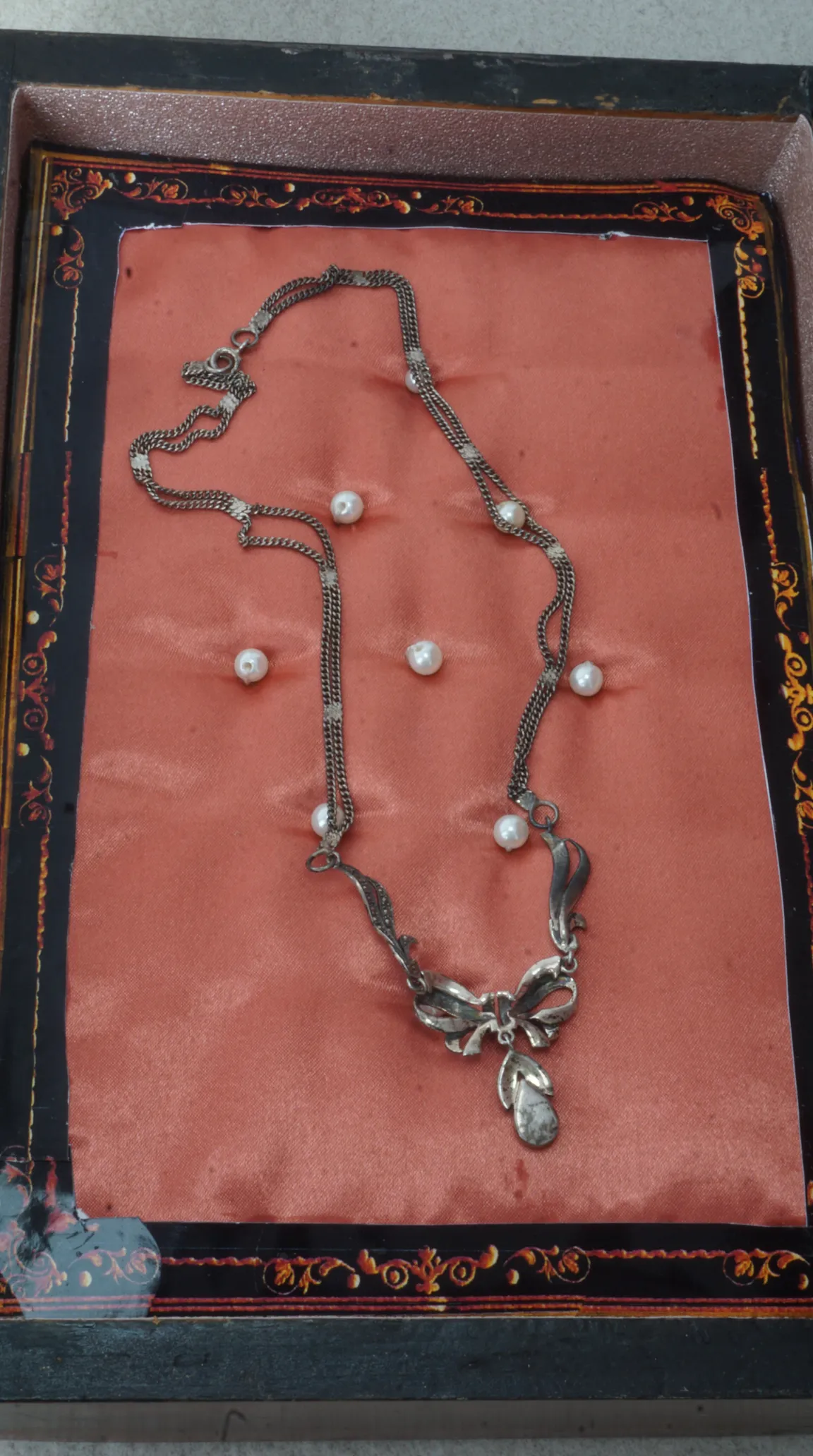 Vintage silver marcasite bow necklace with pearl accents on peach satin.