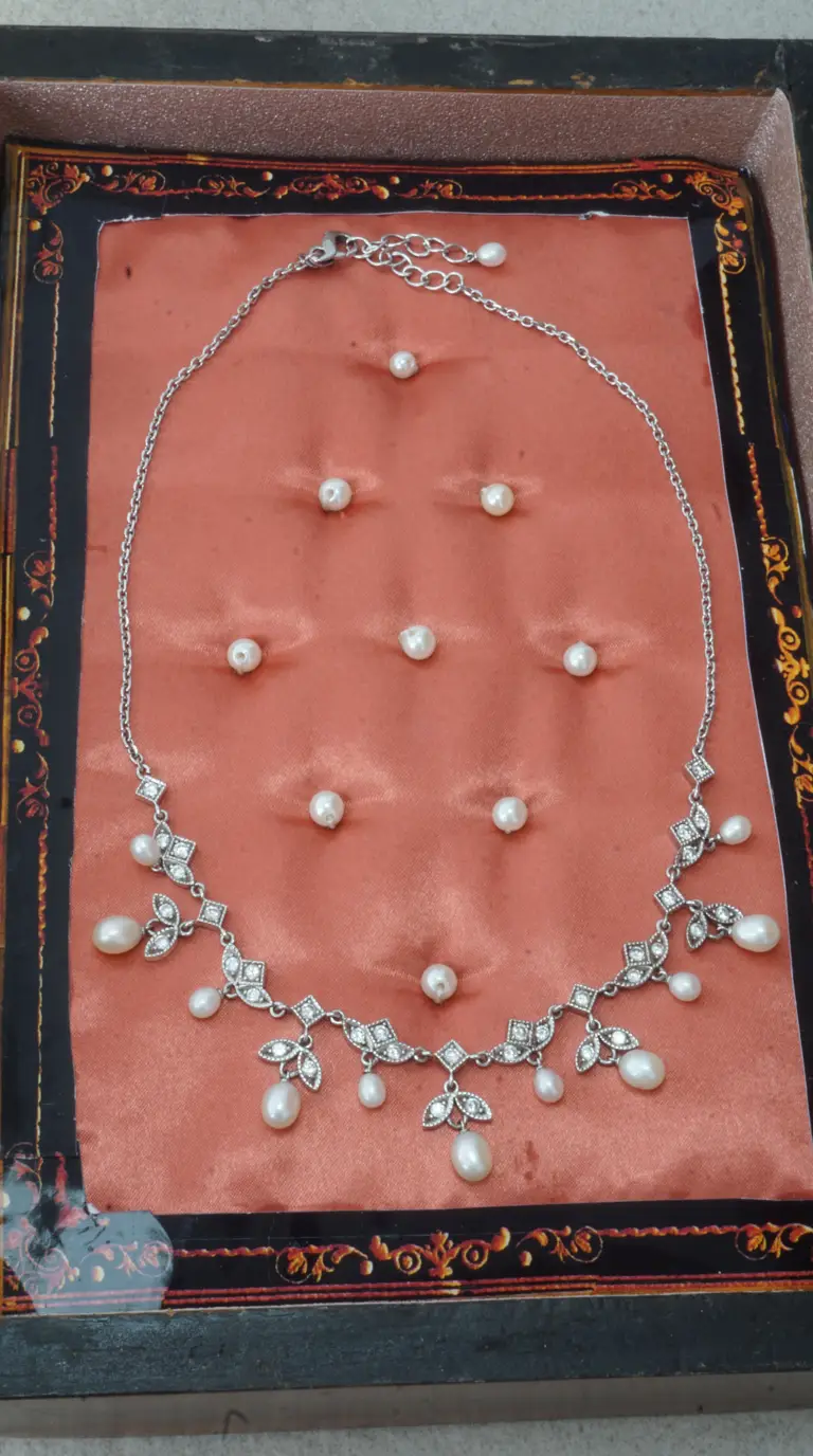 Vintage silver tone pearl and rhinestone necklace with delicate floral accents on salmon satin in ornate display box.