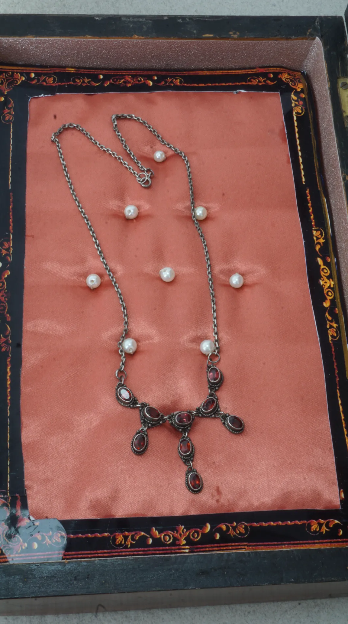 Vintage sterling silver garnet and pearl drop necklace on peach fabric in ornate display box