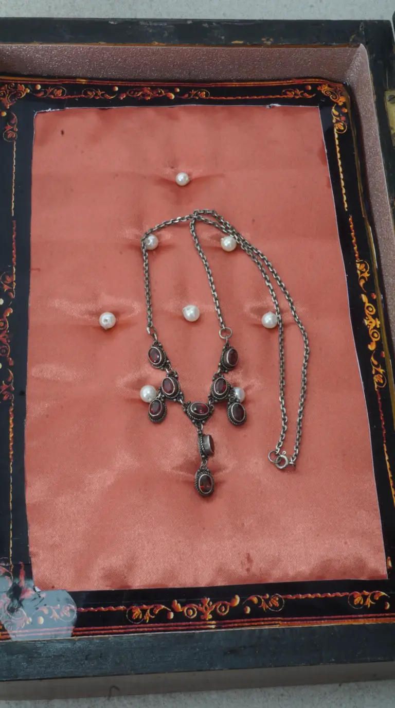 Vintage sterling silver necklace with oval red garnet gemstones and white pearls, displayed on salmon satin.