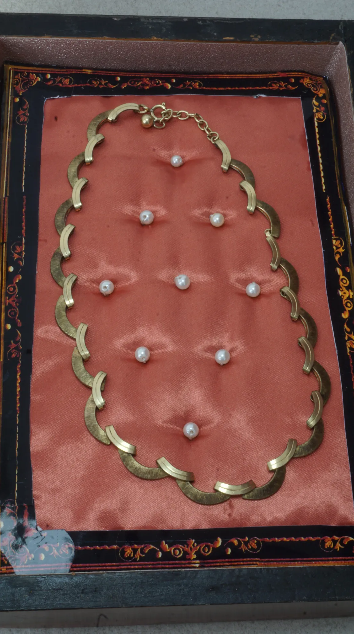 Vintage gold-tone geometric crescent link necklace on peach satin in ornate jewelry box.