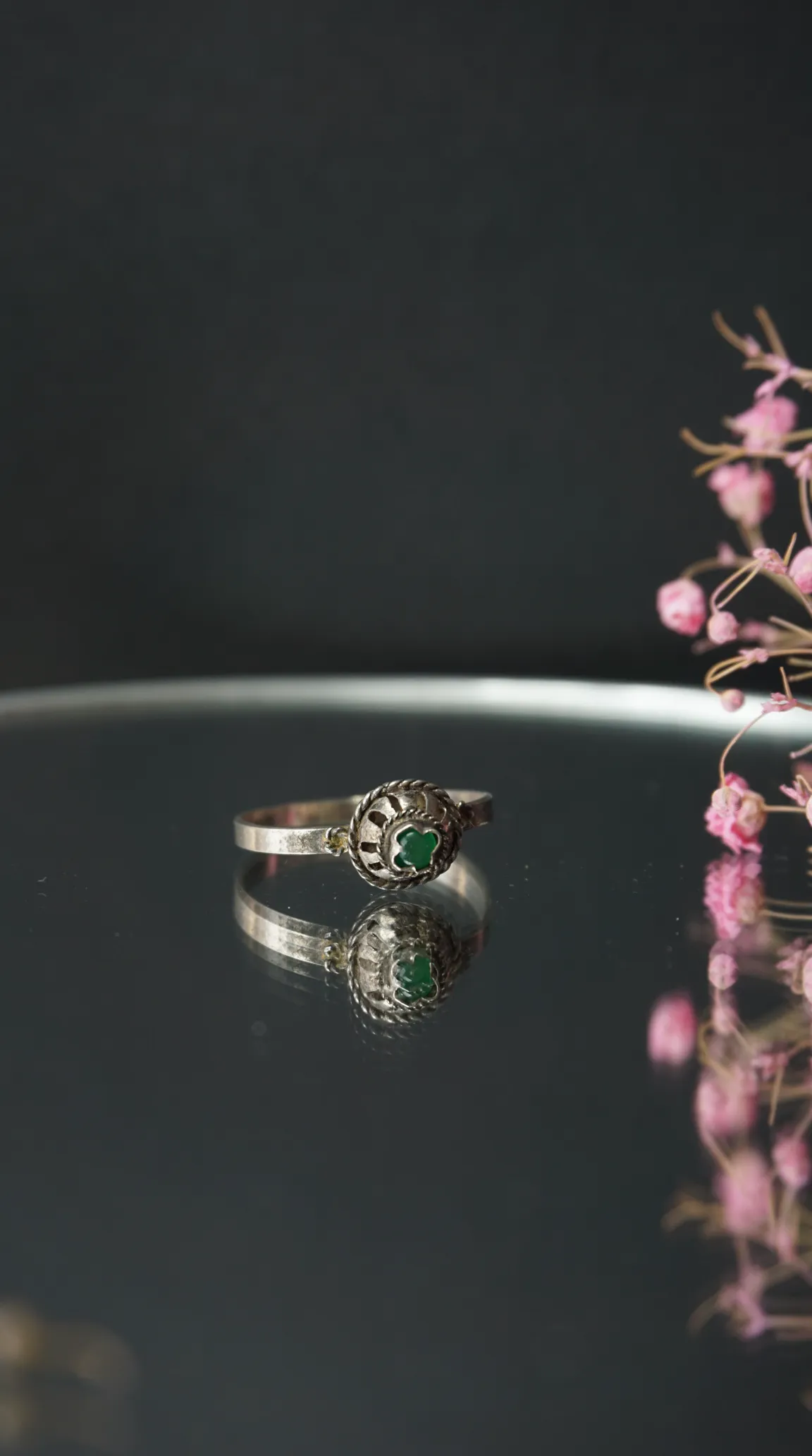 Vintage silver ring with green clover-shaped stone and intricate filigree design, antique jewelry.