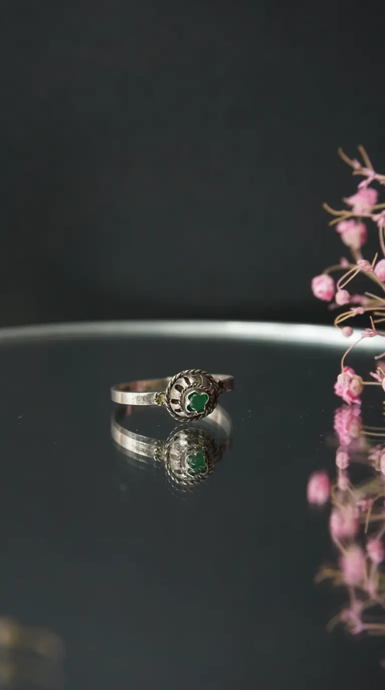 Vintage silver ring with green clover-shaped stone and intricate filigree design, antique jewelry.