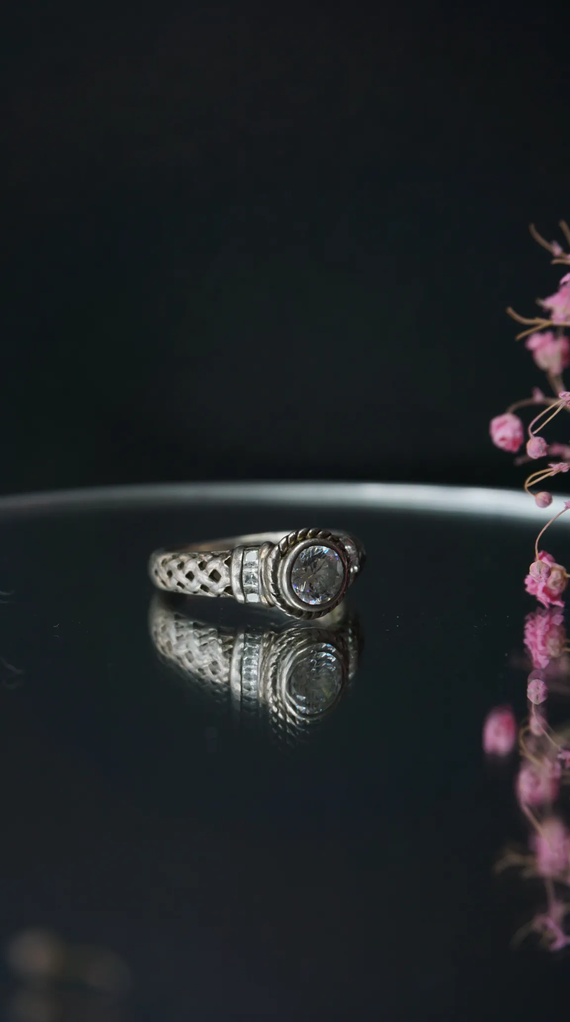 Vintage sterling silver ring with clear round gemstone, intricate Celtic knot details, and side accent stones