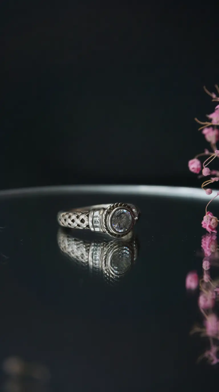 Vintage sterling silver ring with clear round gemstone, intricate Celtic knot details, and side accent stones